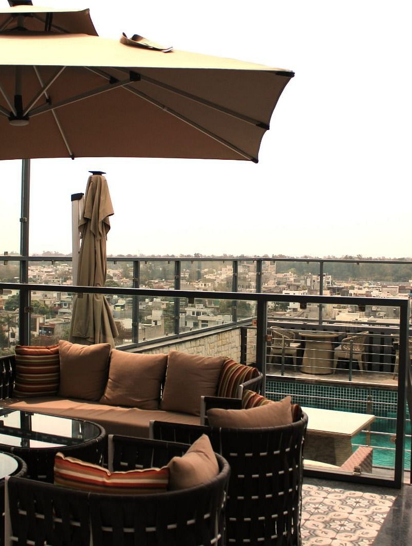 A rooftop lounge with a spacious patio and an adjacent swimming pool at BluSalzz Residence, Amritsar